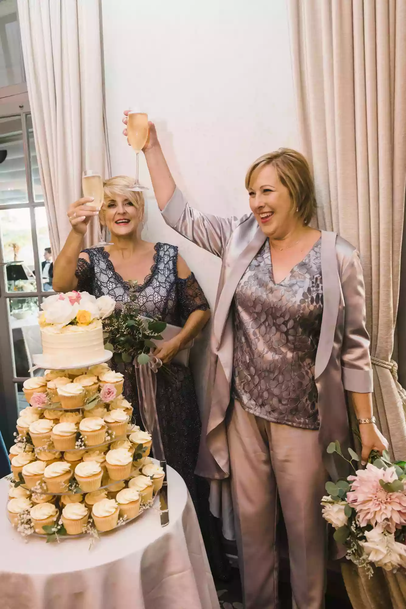 2 brides toasting each other in front of their wedding cake