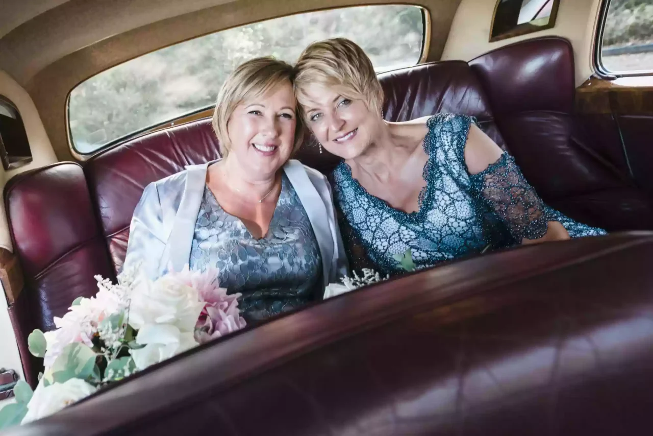 2 brides sitting in the back of a rolls royce