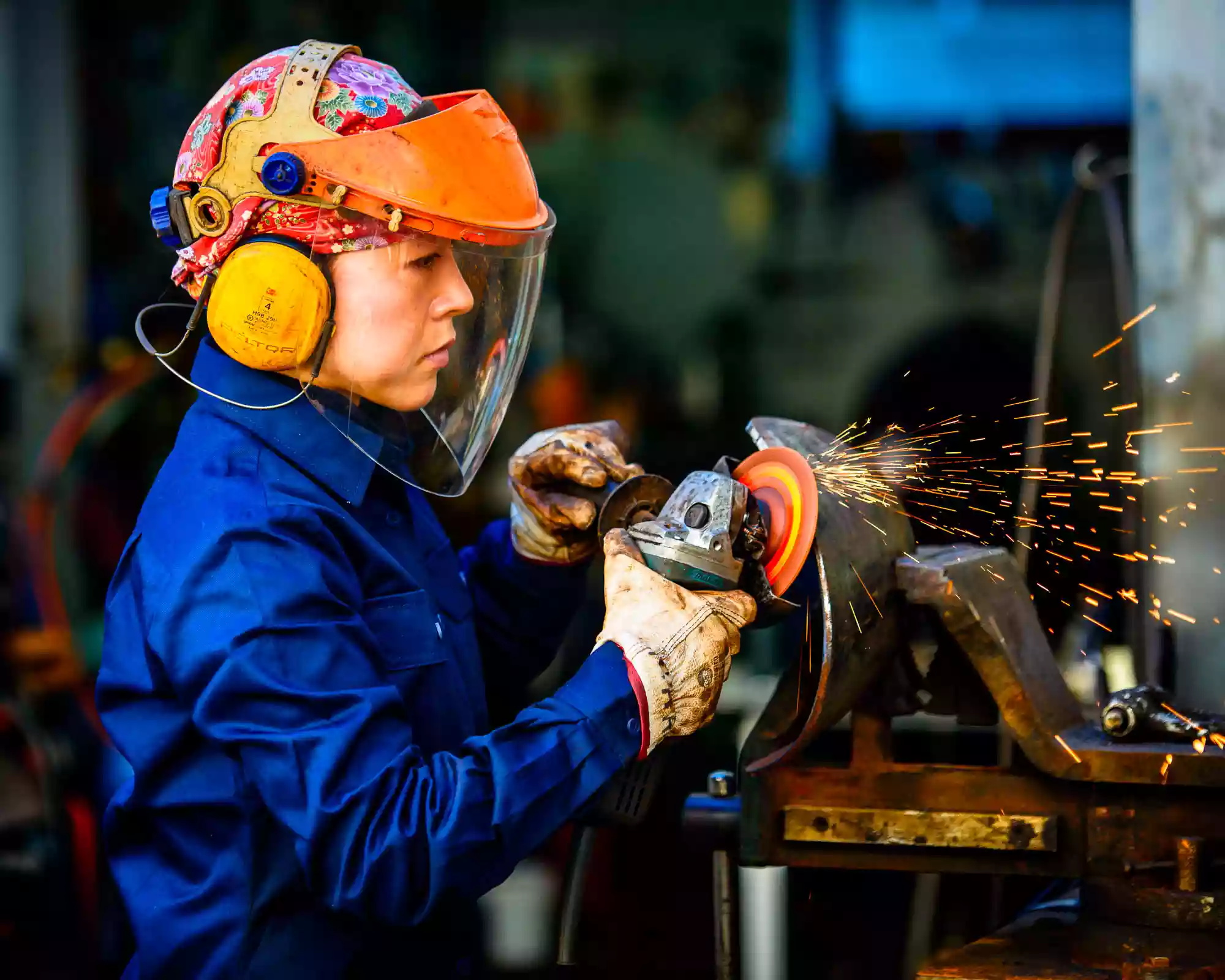 a Japanese woman sculptor welding her metal sculpture, using metalwork gear